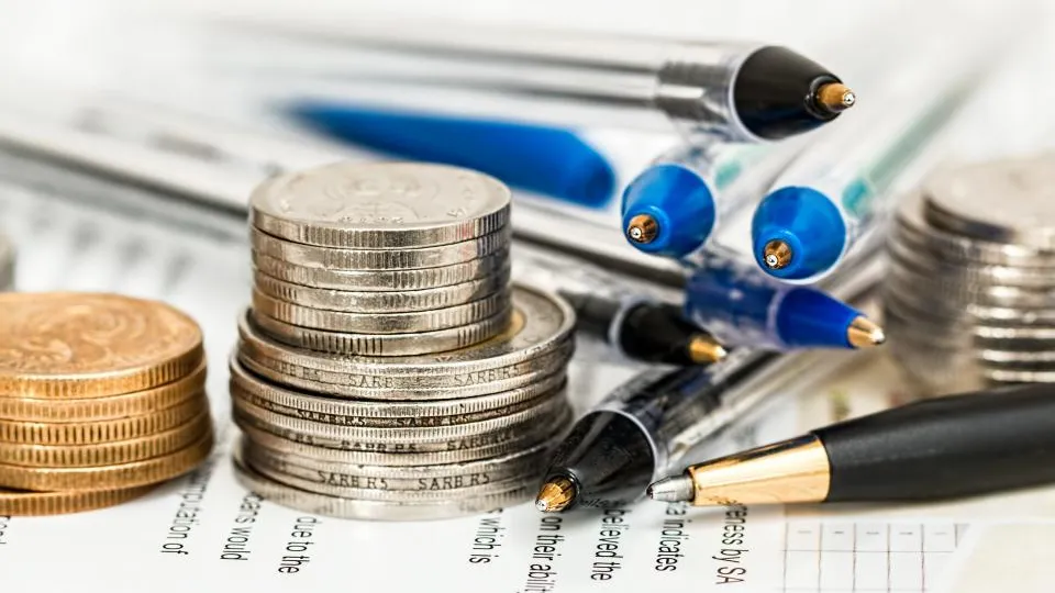 Stacks of coins and pens on paperwork, planning a website budget