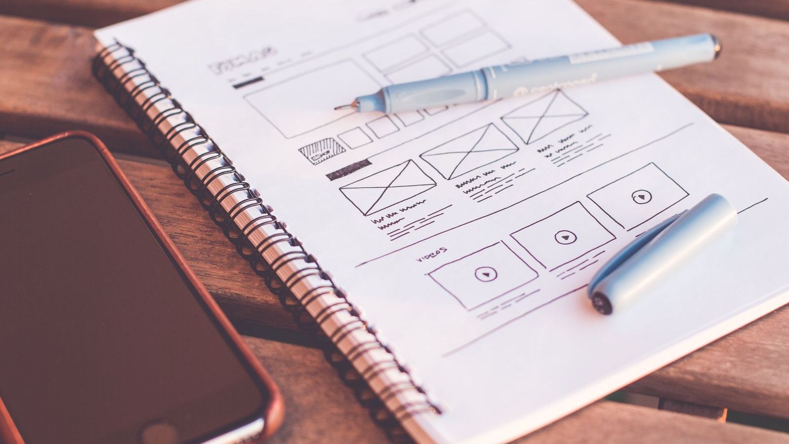 A website layout sketch in a notebook next to a phone – designing a website